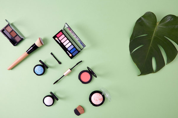 Makeup products on a green background: a variety of cosmetics displayed on a vibrant green surface.