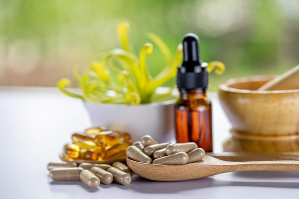 A wooden spoon with pills and a bottle of vitamin oil, essential for daily health and wellness.